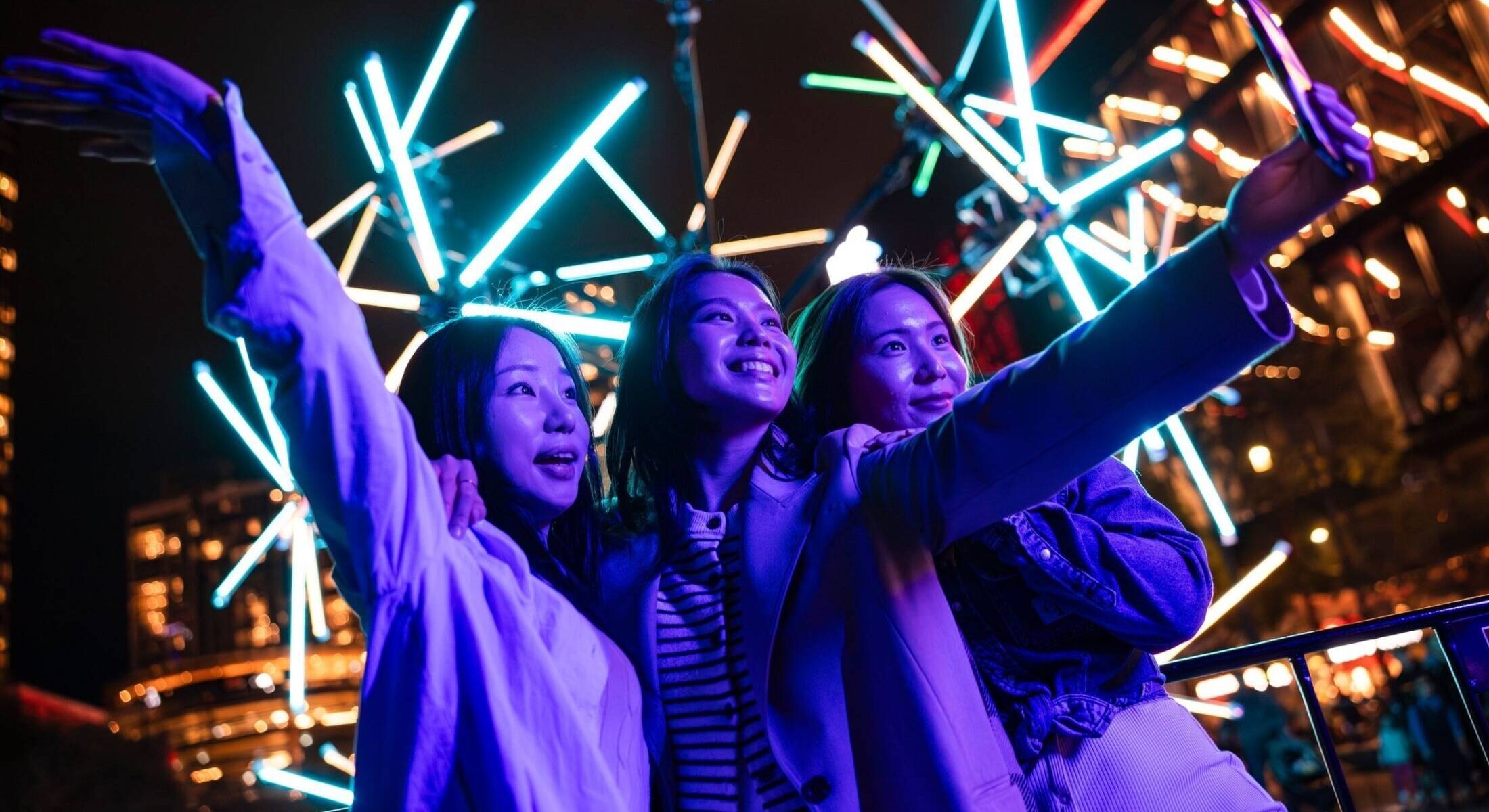 Friends enjoying the lights and sounds of 'Neuron' in Darling Harbour during Vivid Sydney 2024.